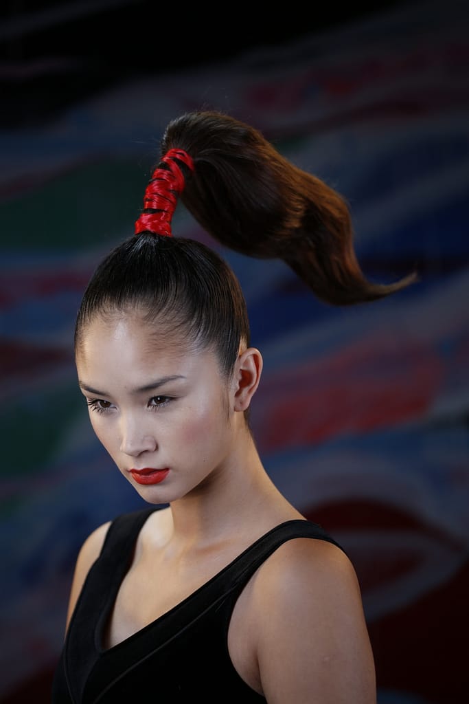 une queue de cheval dressée sur le dessus de tête liée par un bandeau de cheveux rouge, inspiré des pinceau,’ japonais