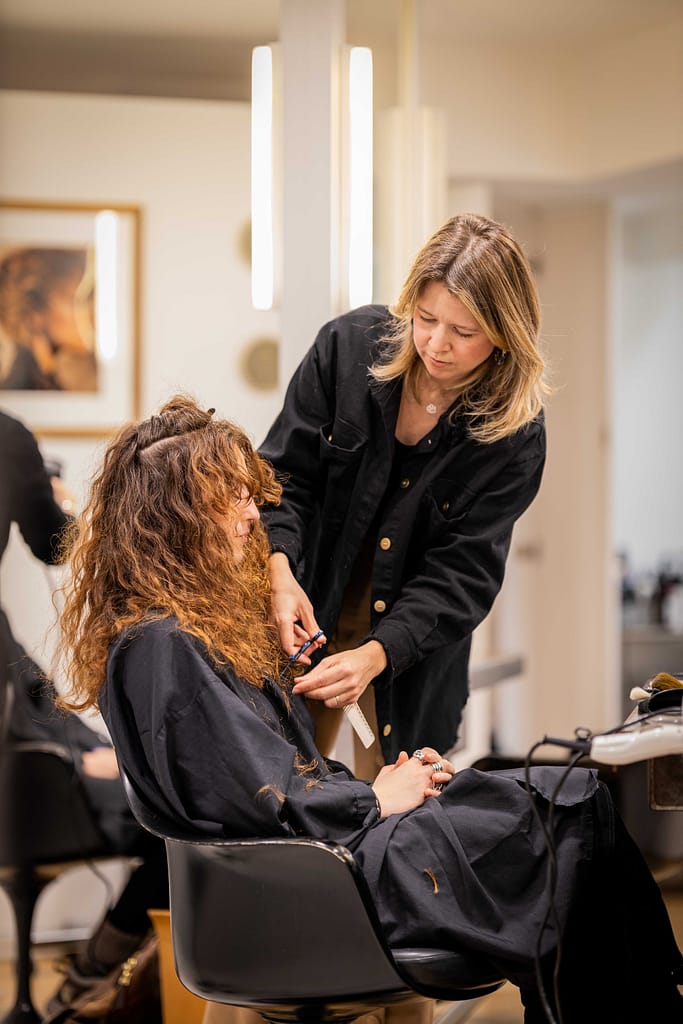 Massato coiffeur Senior pour un relooking coiffure. Elle sculpte la coiffure d'une femme aux cheveux long d'un blond vénitien après sa coupe de cheveux à paris 6
